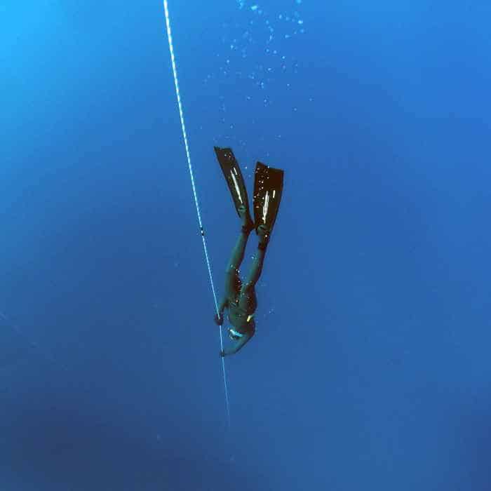 Competitive freediver plunging to the depths of the ocean using freediving line.