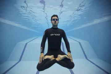 Freediver floating in pool wearing open cell wet suit.